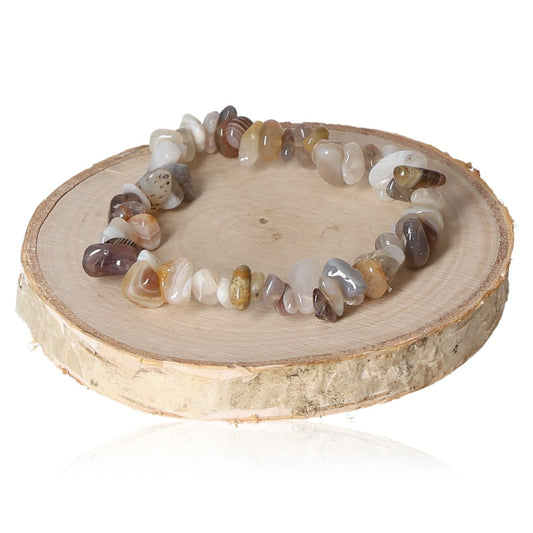 Botswana agate chip bracelet on wooden display, showcasing natural stone variations and earthy tones.