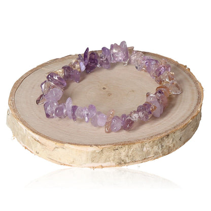 Ametrine bracelet with purple gemstone chips on wooden slice background.