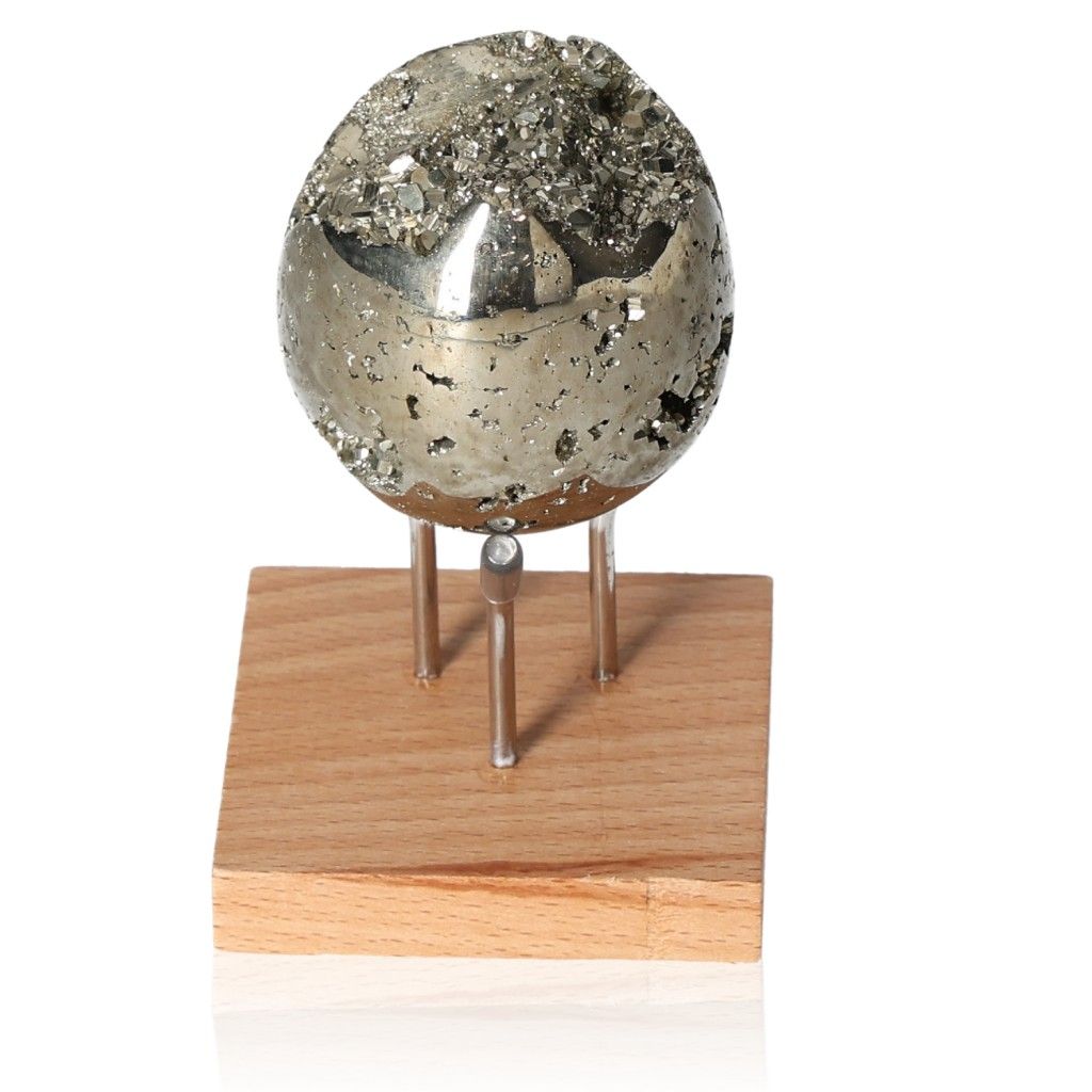 Pyrite egg on wooden stand, symbolizing mental independence and courage for goal achievement.