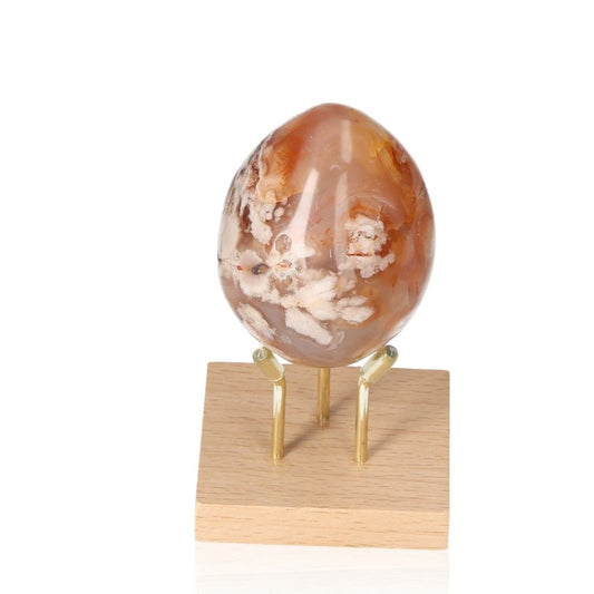 Flower Agate Egg with floral patterns on wooden stand showcasing emotional harmony benefits.