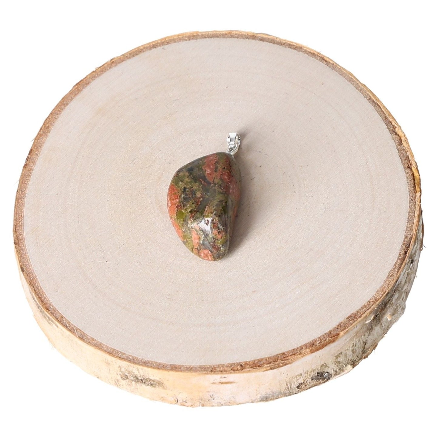 Unakite tumbled pendant on wooden slice display for jewelry.