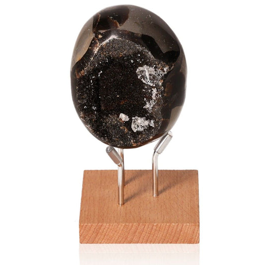 Unique septarian stone on a wooden stand, showcasing its distinctive dark patterns and rich symbolic meanings.