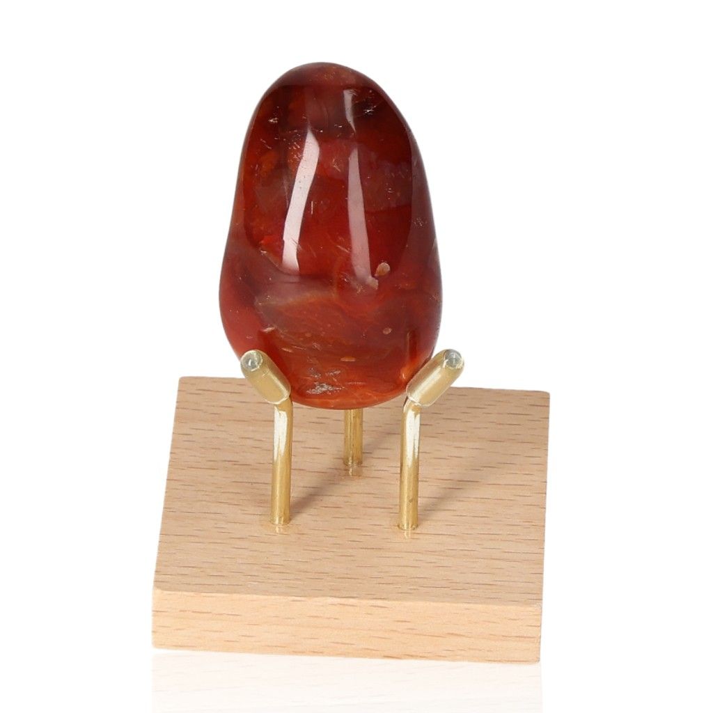 Carnelian gemstone on wooden stand, an energy booster for motivation and strength, ideal for facing challenges with courage.